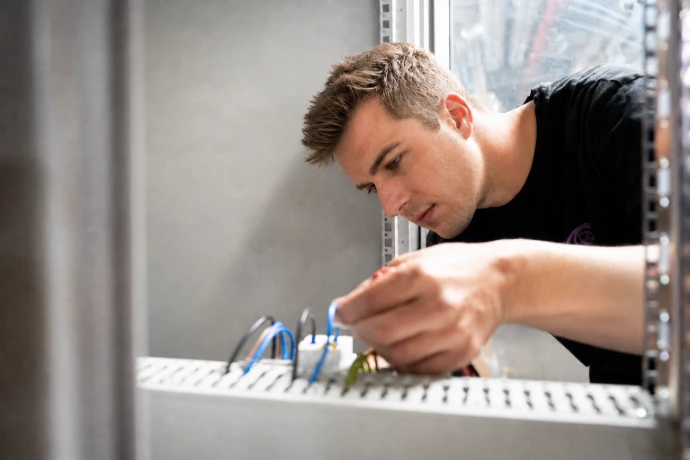 Technieker van The Belgian sluit bekabeling aan in een technische kast