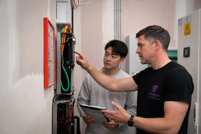 Technieker van The Belgian geeft uitleg over een technische installatiekast